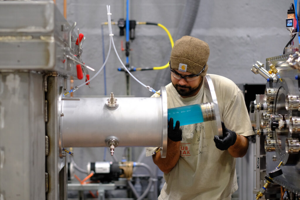 A Xcimer employee inserts a copper sulfate solution resistor into a pulsed power system — part of the power supply for the laser amplifier.